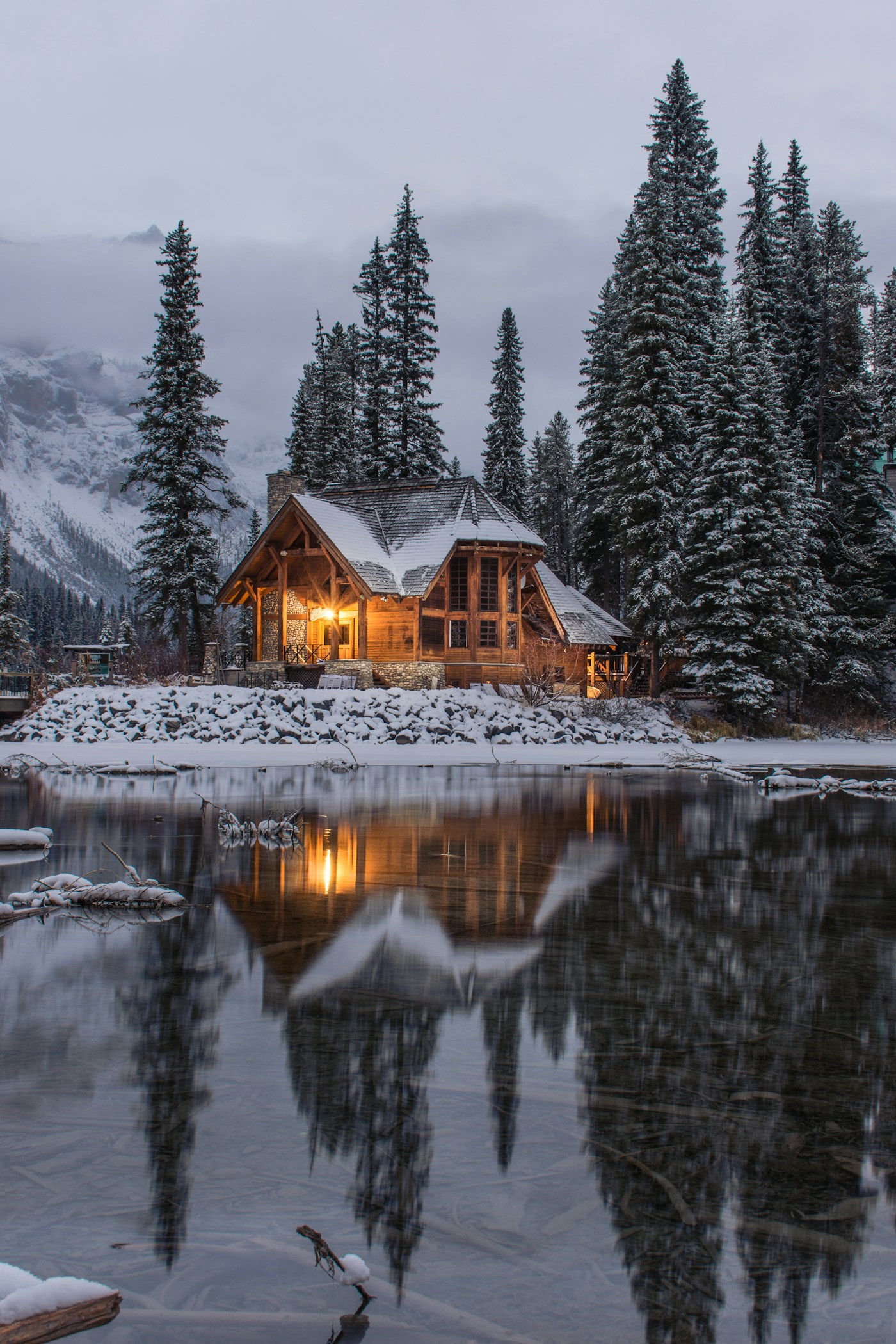 Warmly lit timber cabin beside a lake in a snowy forest